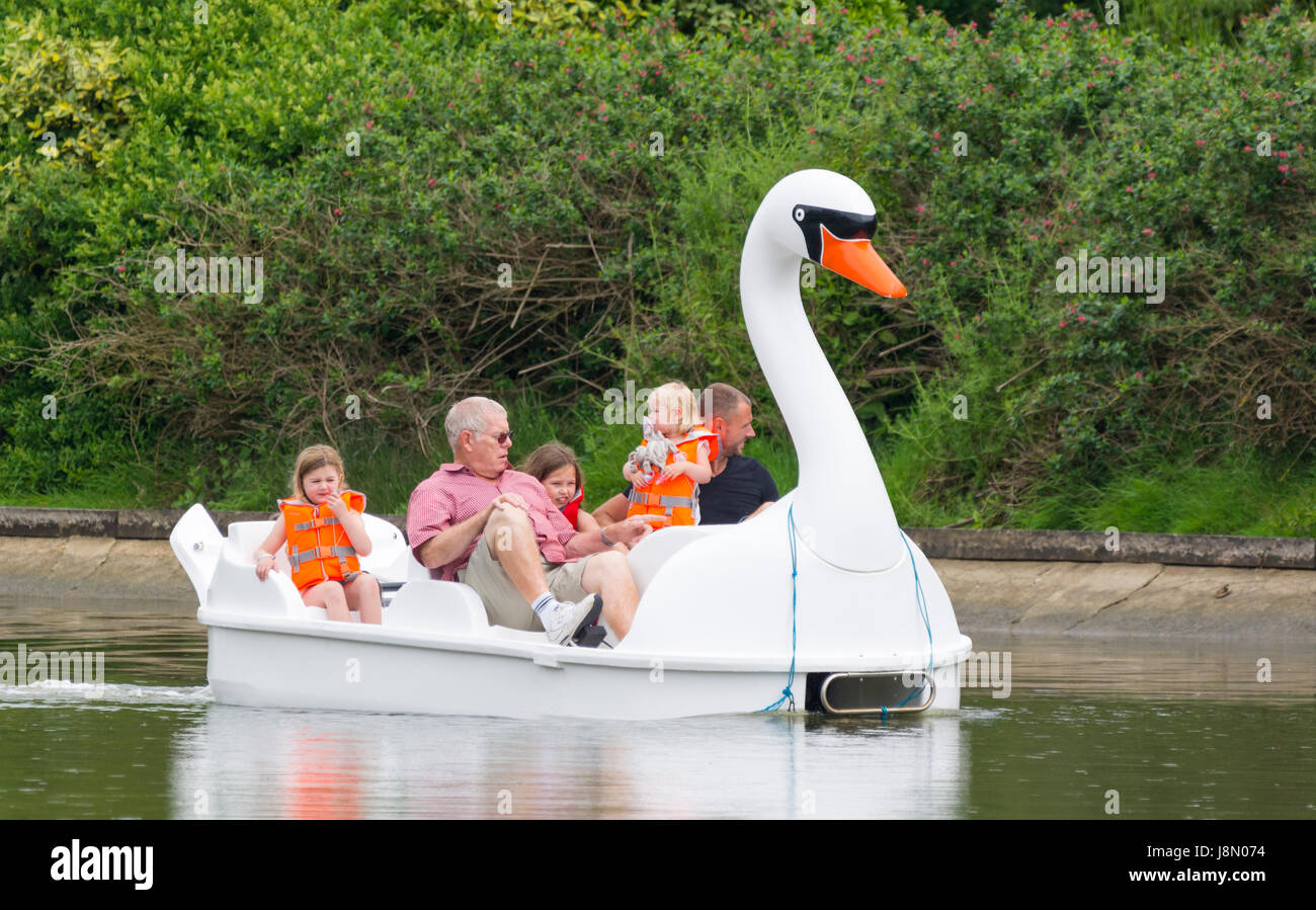 Famiglia in un pedalò sul lago in barca su una primavera piovosa giornata nel Regno Unito. Foto Stock