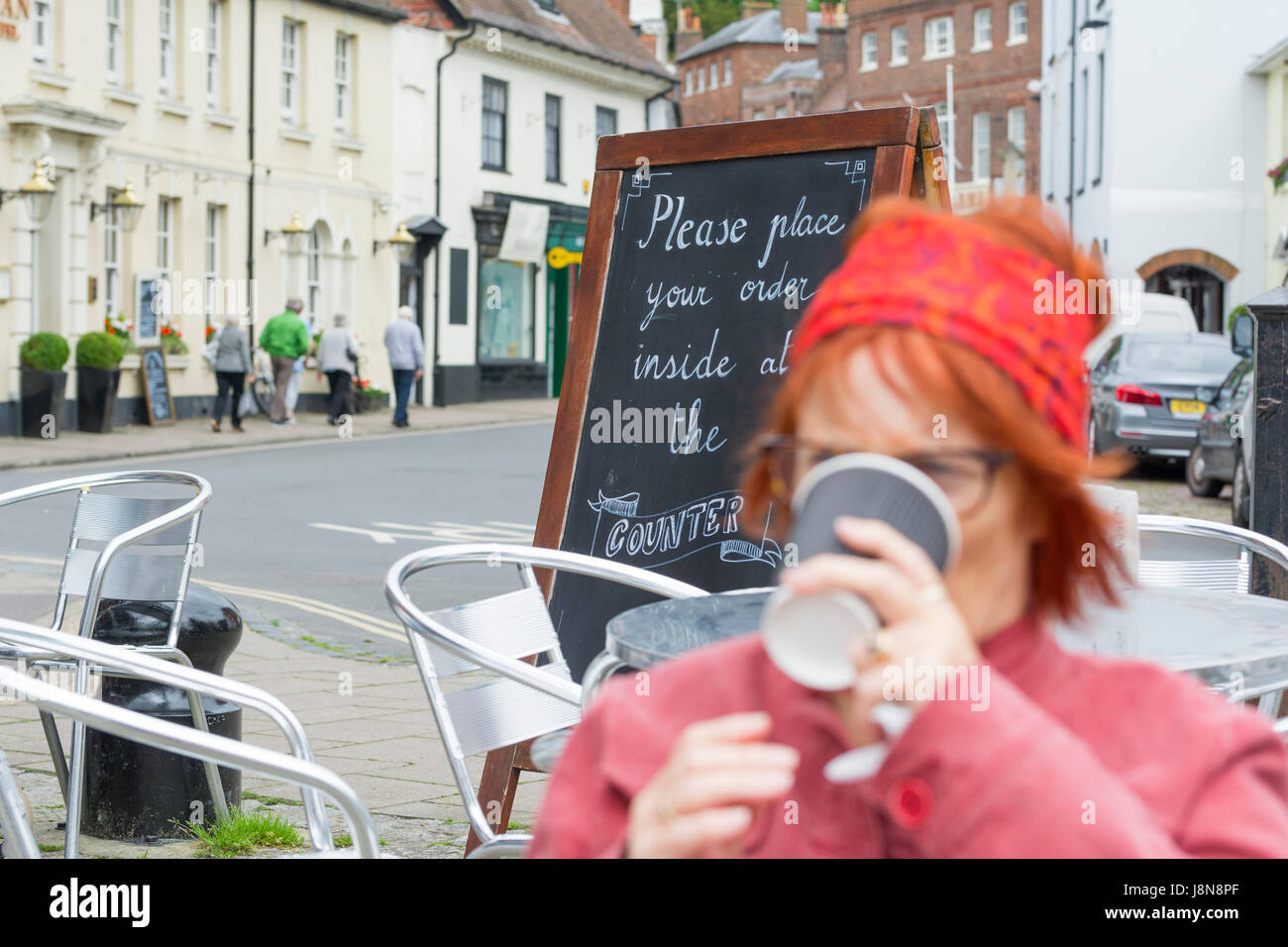Una signora di bere il caffè al di fuori di un bar nel Regno Unito. Foto Stock