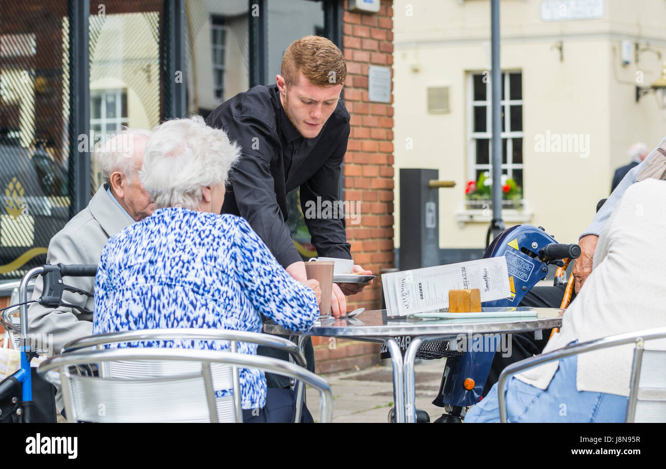 Scena quotidiana di turisti che vengono serviti caffè in un caffè all'aperto nel Regno Unito. Foto Stock