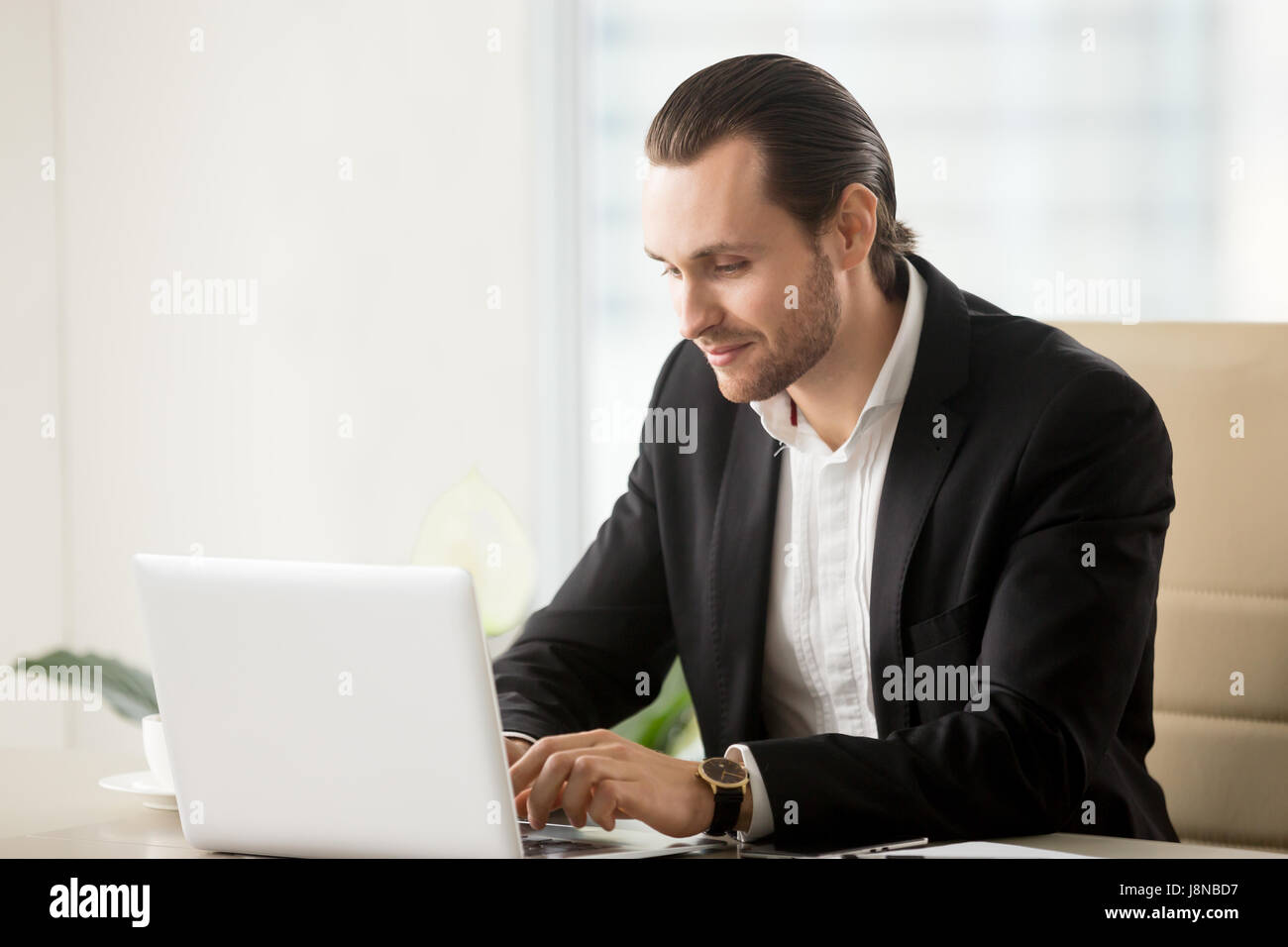 Imprenditore digitando su laptop alla scrivania in ufficio. Lavoratore di ufficio discute con i colleghi di politica aziendale in chat. Imprenditore conduce le trattative onl Foto Stock
