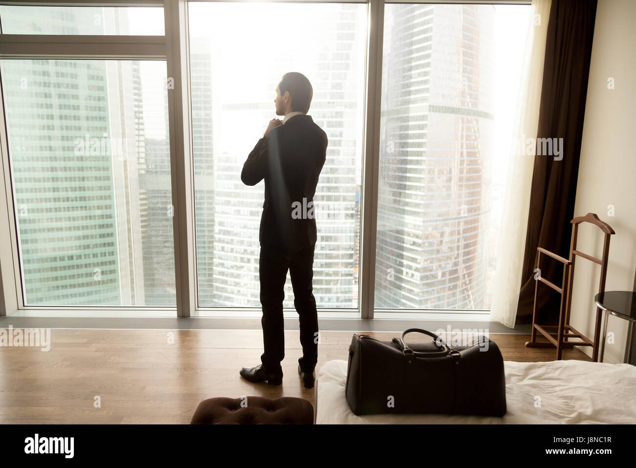 Imprenditore gode di vista da finestra in camera di albergo Foto Stock