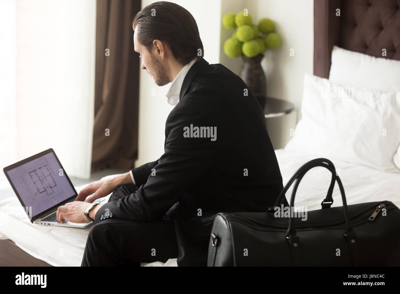 Controlli esecutivi tenuta piano su laptop in hotel Foto Stock