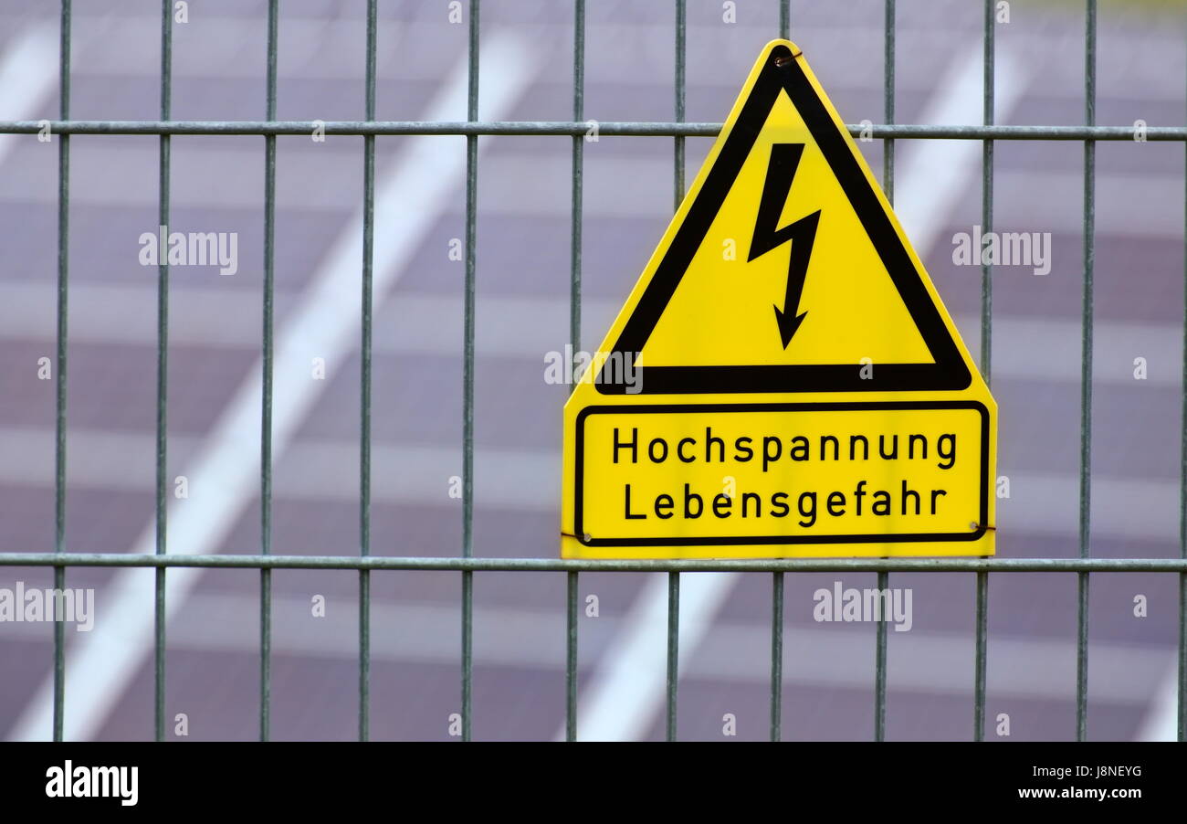Segno con le parole di alta tensione - pericolo di vita in tedesco nella parte anteriore dei pannelli solari. Foto Stock