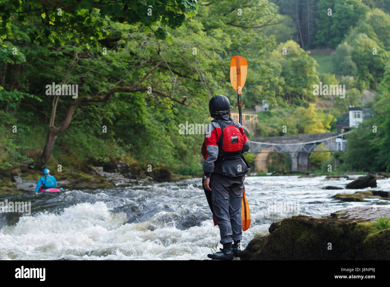 Kayaker femmina in piedi e guardare le rapide sul alla coda di serpenti vicino al Ponte delle catene sul fiume Dee in Galles del Nord Foto Stock