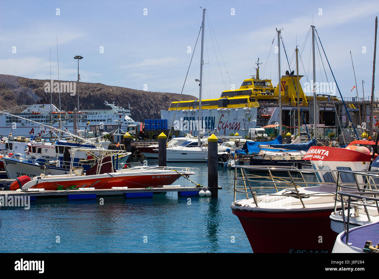 Barche colorate confezionate in porto e marina a Los Cristianos ferry terminal in Tenerife in una calda giornata estiva Foto Stock