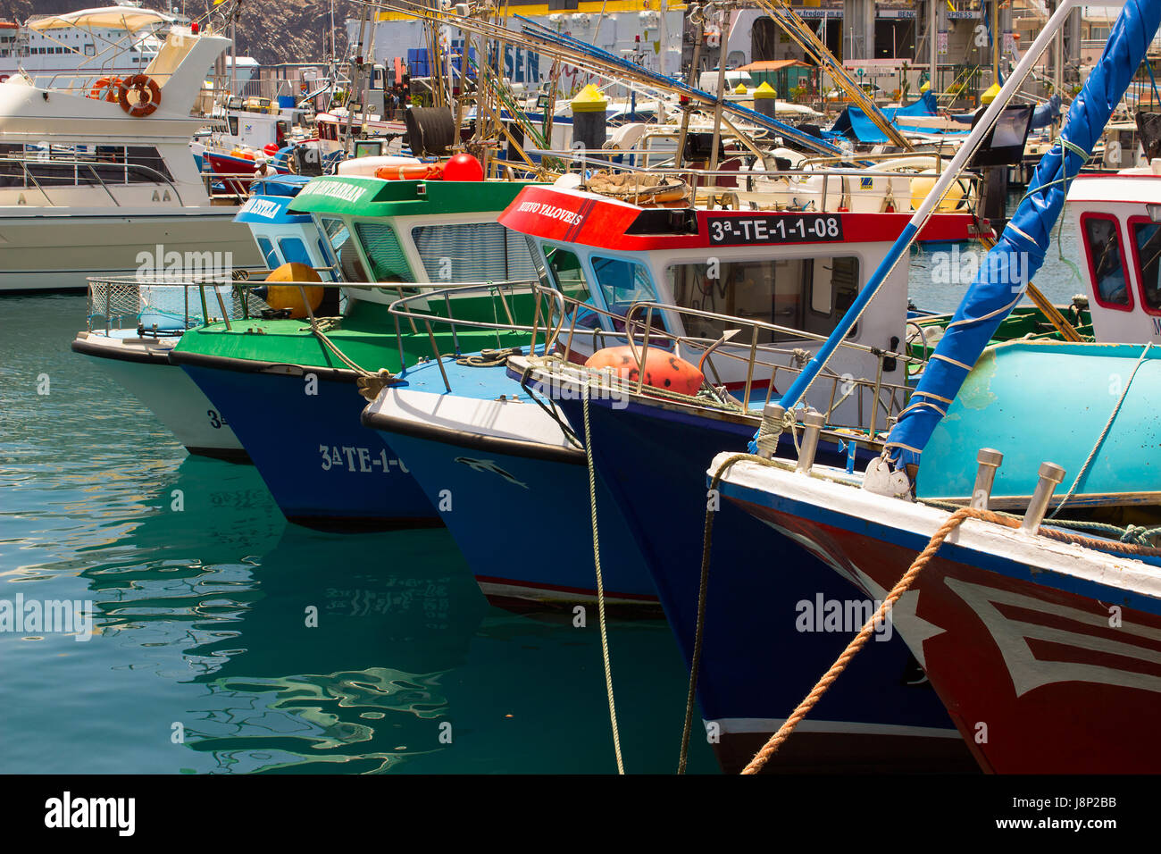 Barche colorate confezionate in porto e marina a Los Cristianos ferry terminal in Tenerife in una calda giornata estiva Foto Stock