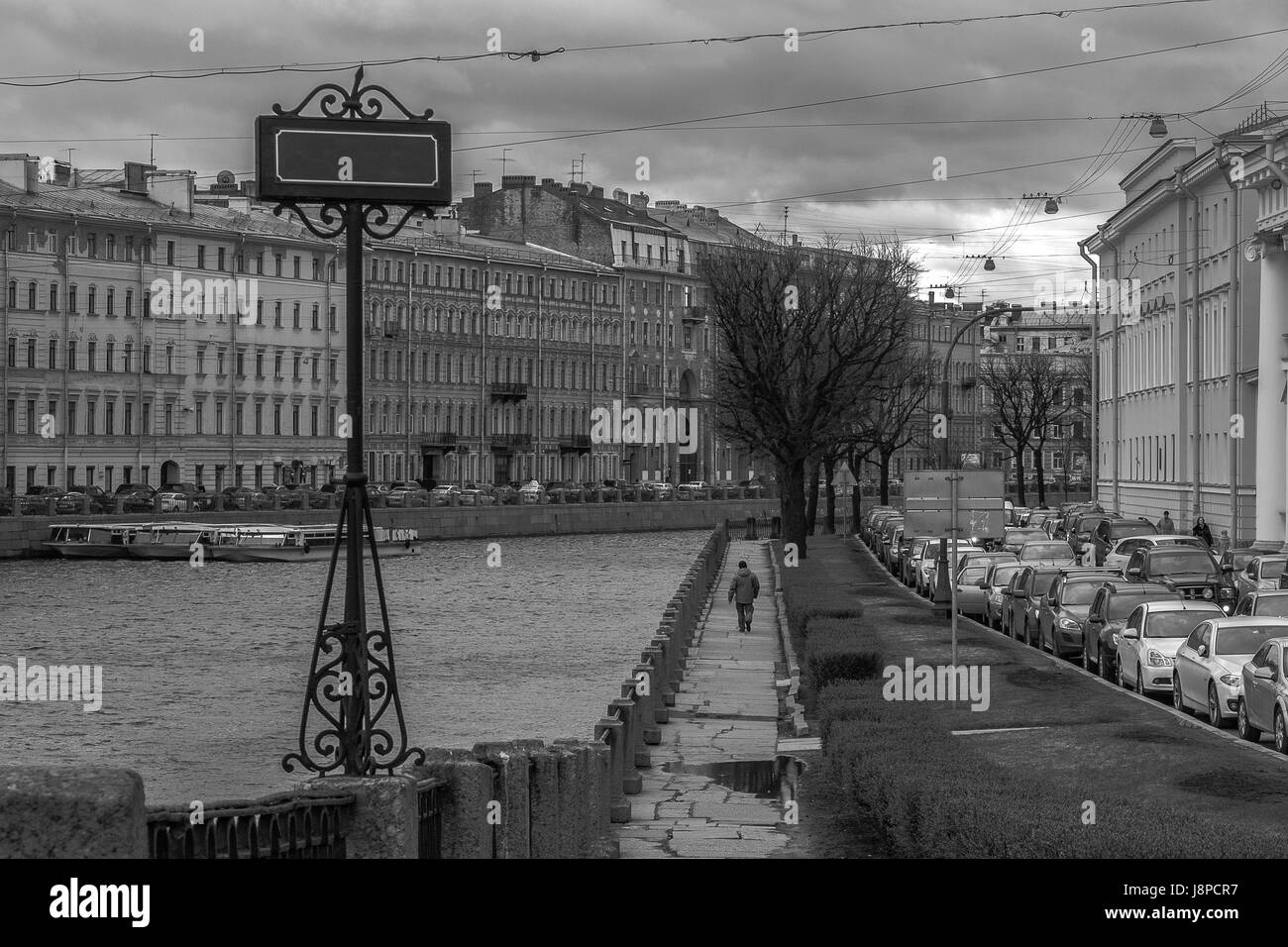 Lonely man walking sulla banca del fiume Neva a San Pietroburgo. Contro la concezione di flusso. Tabella vuota con uno spazio per il testo. Foto Stock