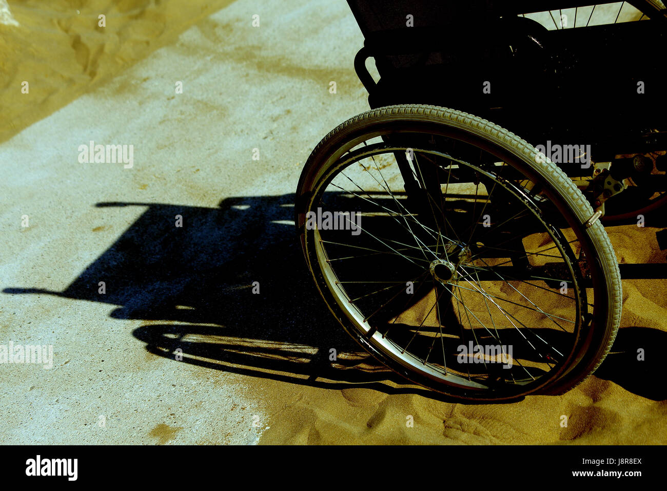 Ombra di sedia a rotelle sulla sabbia della spiaggia Foto Stock