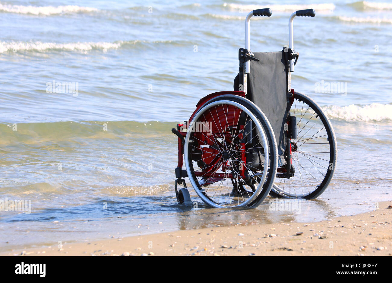 Sedia a rotelle sulla riva del mare in una calda giornata di sole Foto Stock