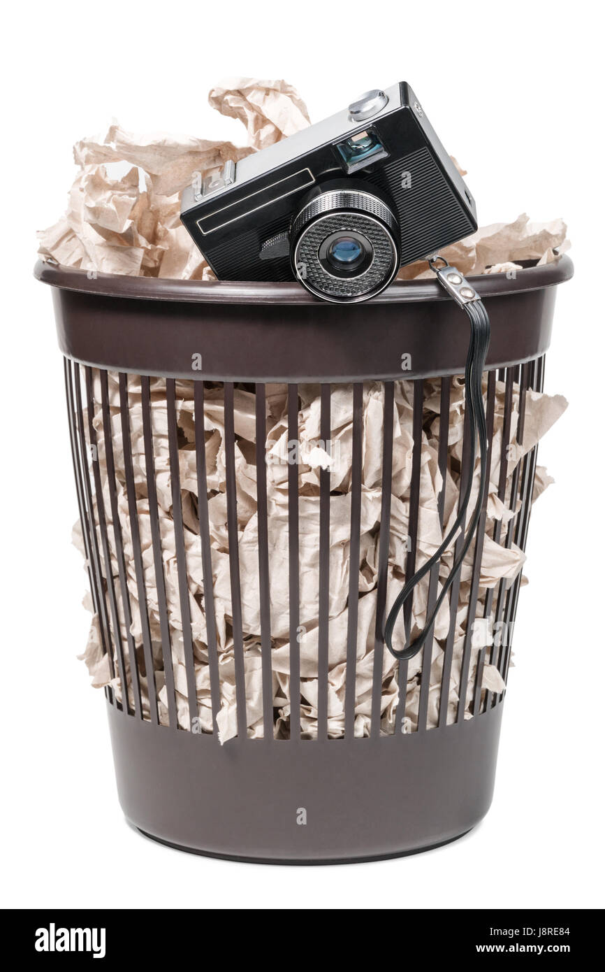Vecchio film camera in un cestino pieno di carta igienica, isolato su uno sfondo bianco Foto Stock