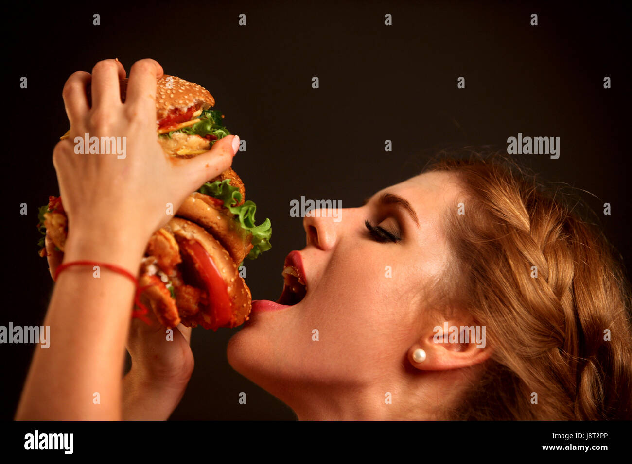 Donna di mangiare hamburger. Studente consumano fast food. Foto Stock