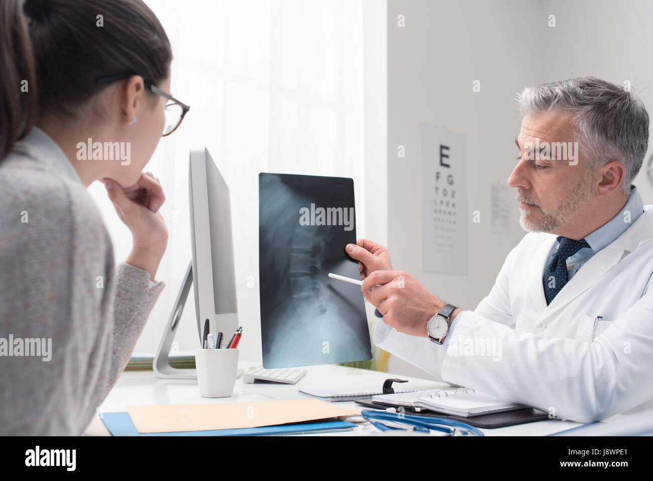 Professional medico radiologo e dando una consultazione per il suo paziente, egli sta esaminando e immagine a raggi x e puntamento Foto Stock