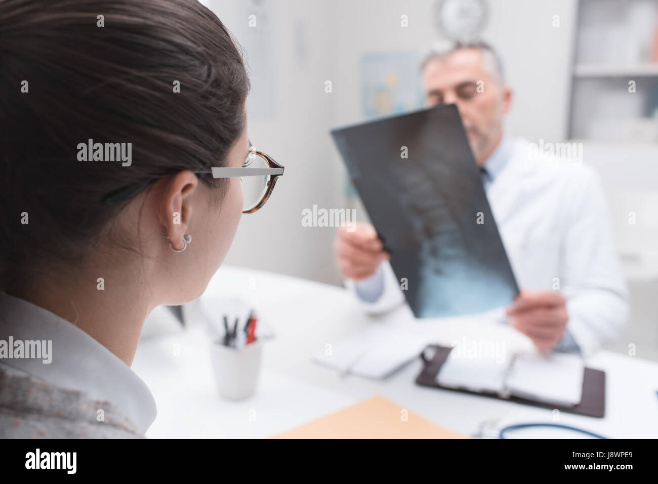 Professional medico radiologo e dando una consultazione per il suo paziente, egli sta esaminando e immagine a raggi x Foto Stock