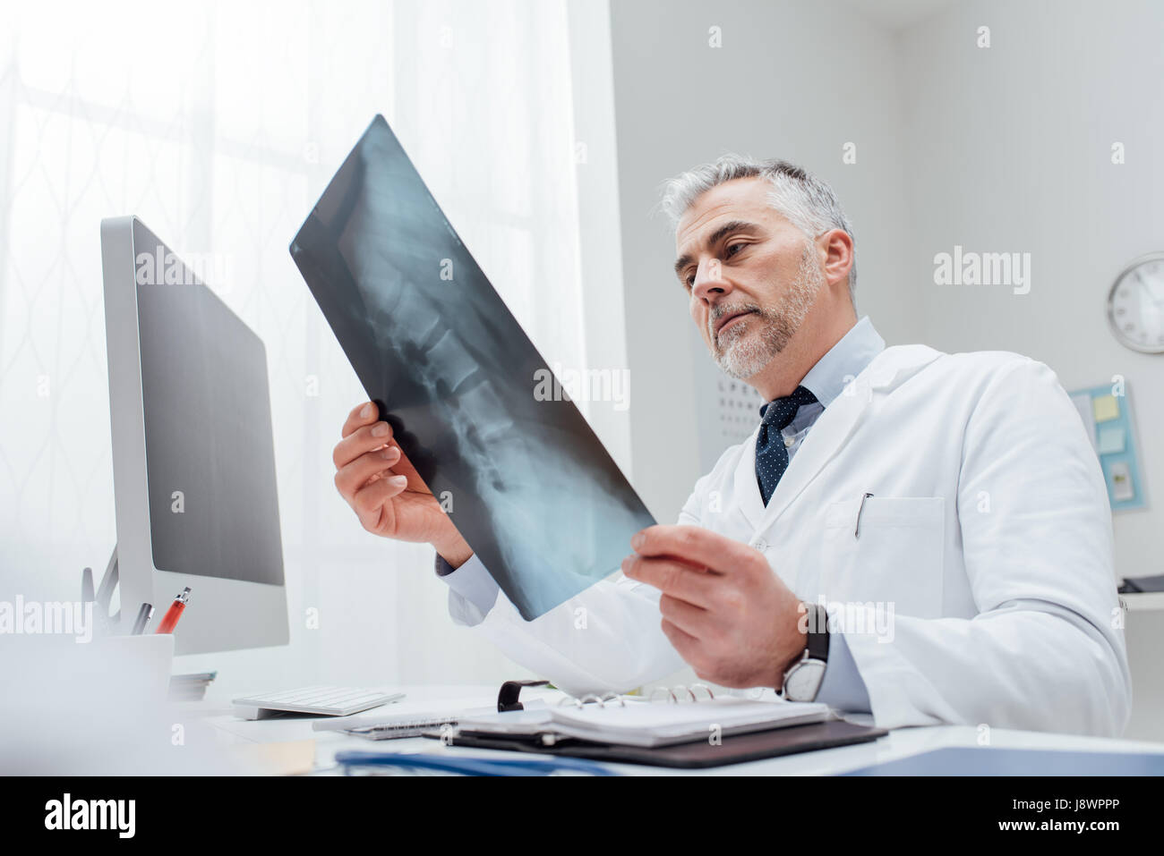 Professional medico radiologo e dando una consultazione per il suo paziente, egli sta esaminando e immagine a raggi x Foto Stock