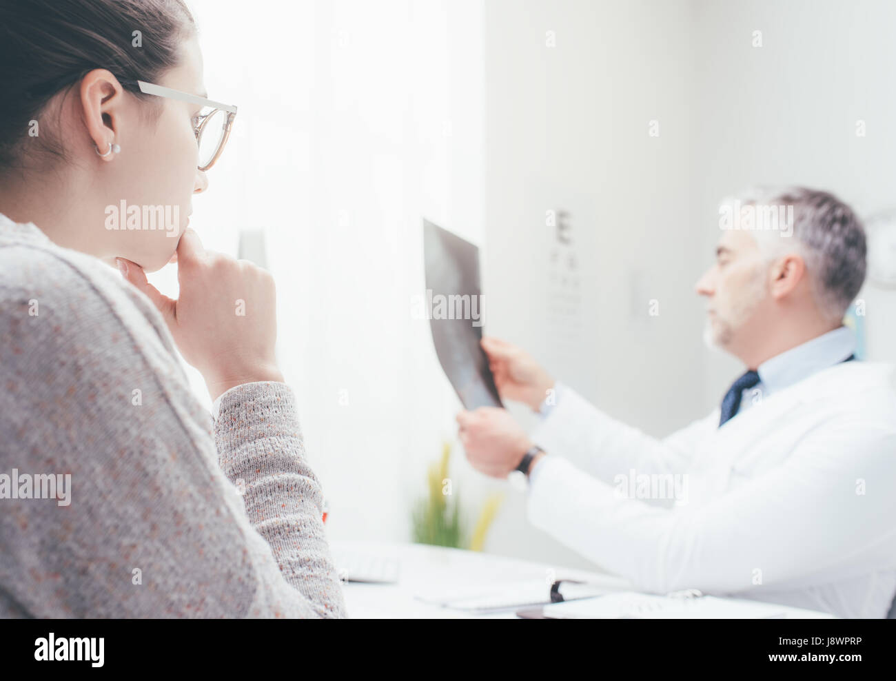 Professional medico radiologo e dando una consultazione per il suo paziente, egli sta esaminando e immagine a raggi x Foto Stock