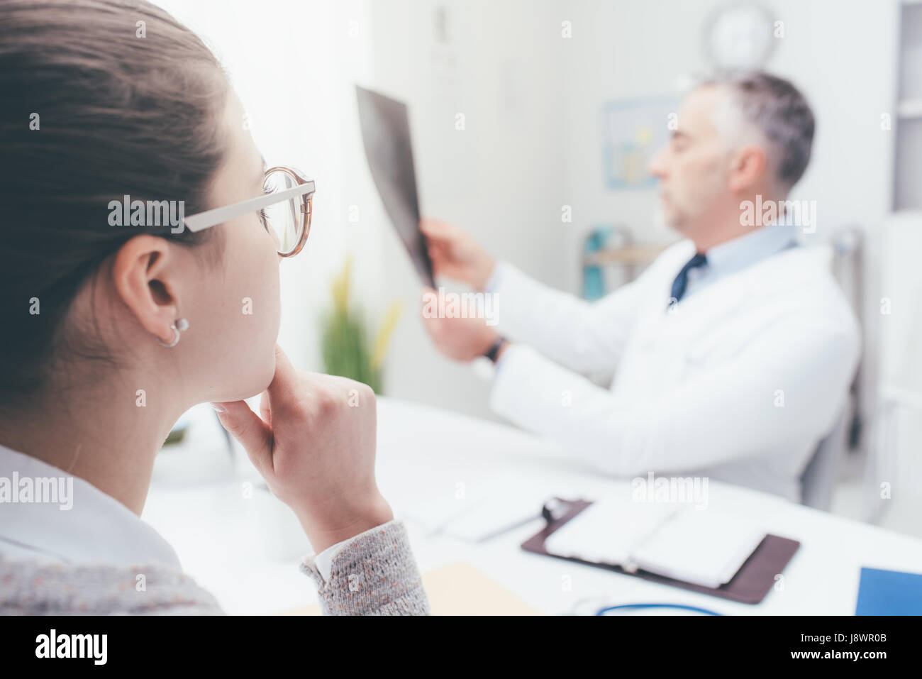 Professional medico radiologo e dando una consultazione per il suo paziente, egli sta esaminando e immagine a raggi x Foto Stock