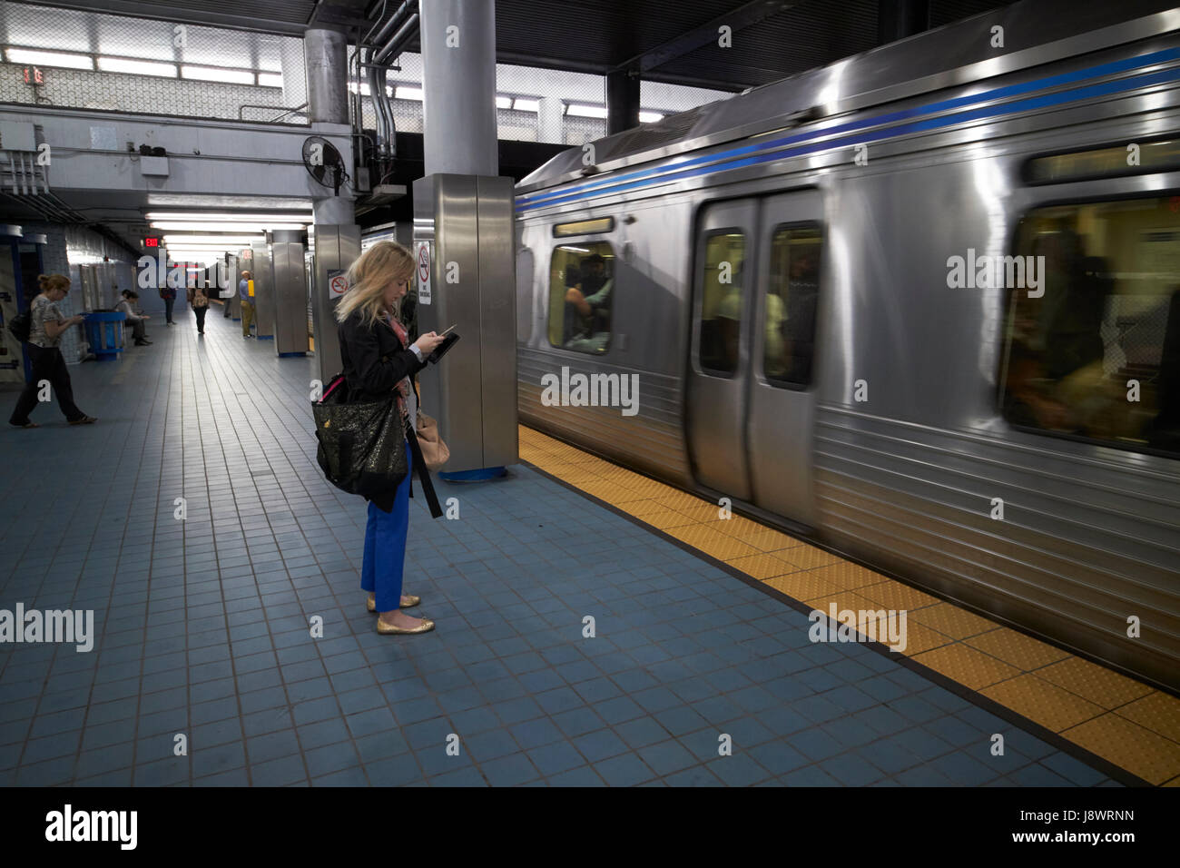 Donna controllare lo smartphone come un treno arriva a setti 2° strada metropolitana stazione Philadelphia STATI UNITI D'AMERICA Foto Stock