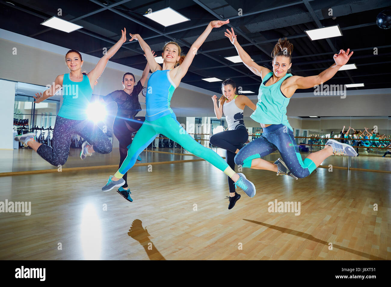 Un gruppo di ragazze salto con sorrisi in palestra Foto Stock
