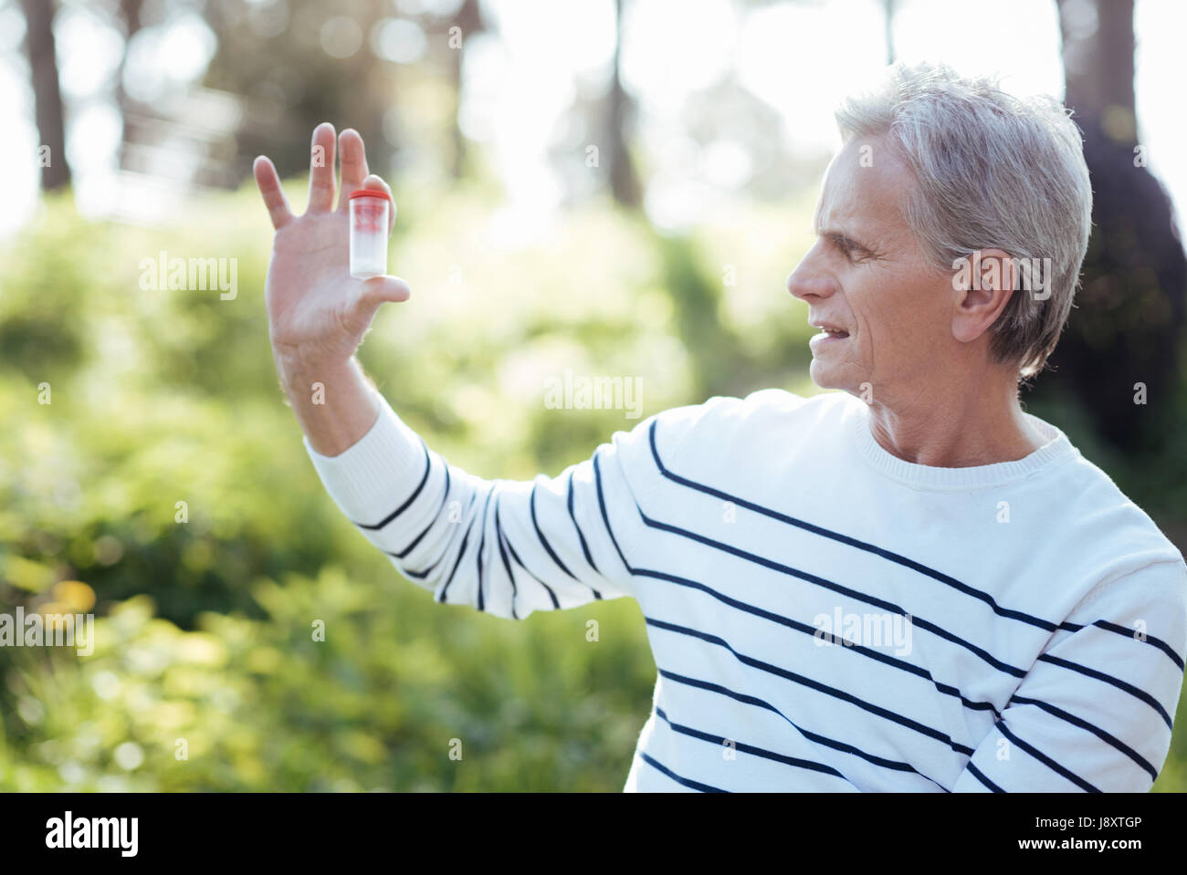 Perplesso titolare di pensione o di rendita tenendo la bottiglia con analgesici esterni Foto Stock