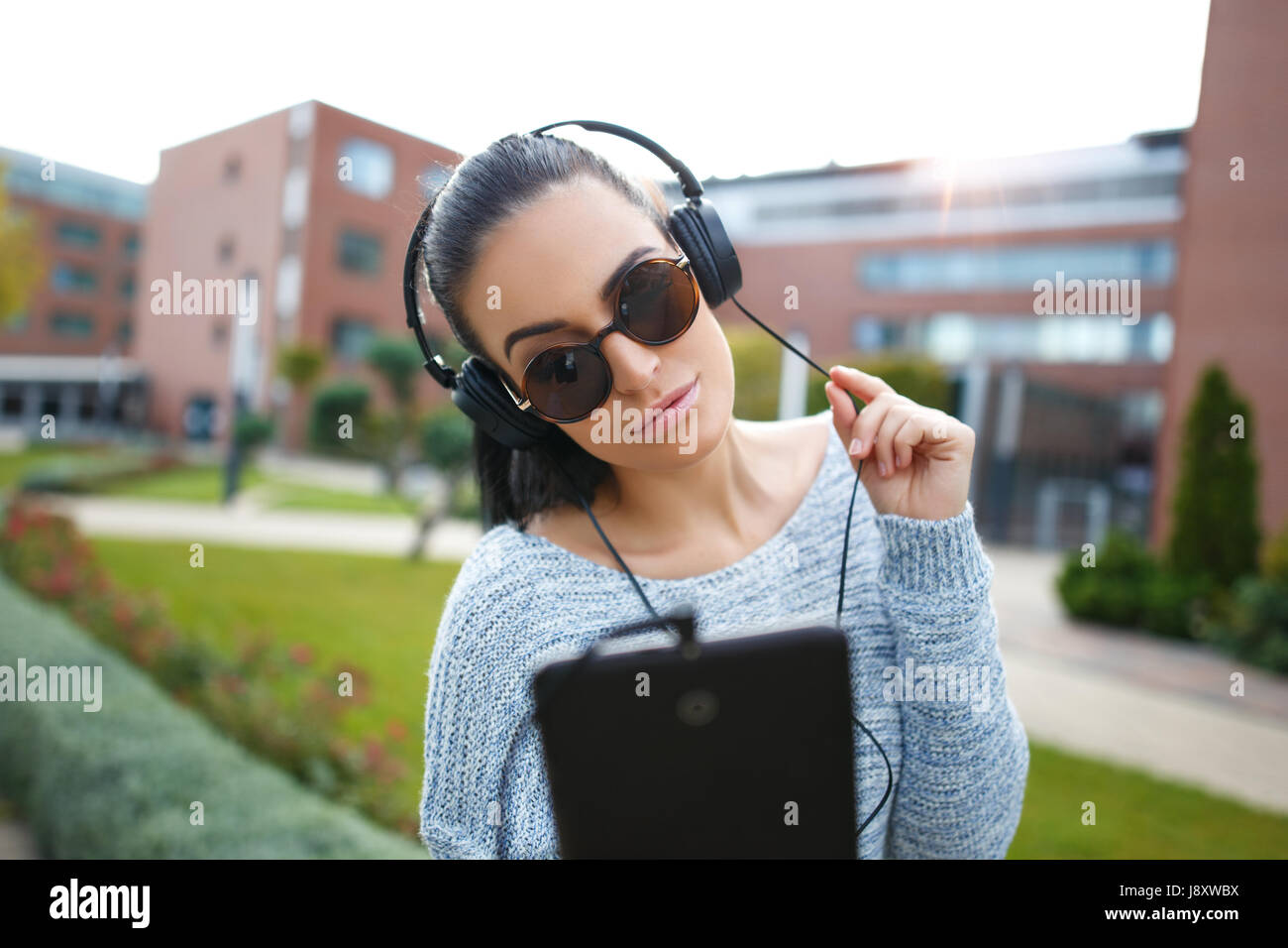 Giovane donna ascoltando musica su tablet nel parco della città Foto Stock
