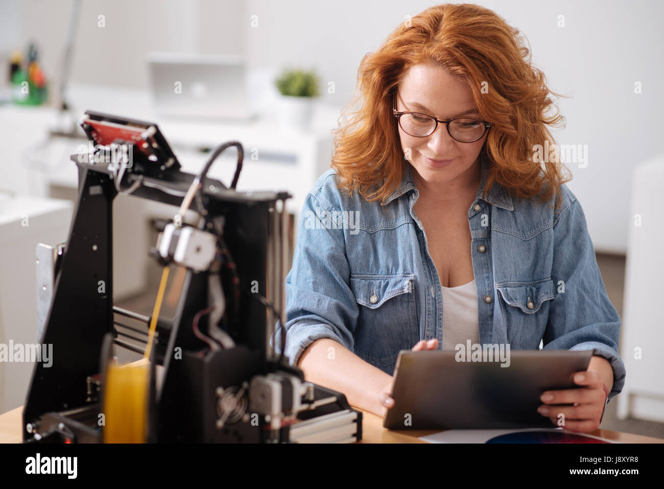 Piacevole donna positiva tenendo un tablet Foto Stock