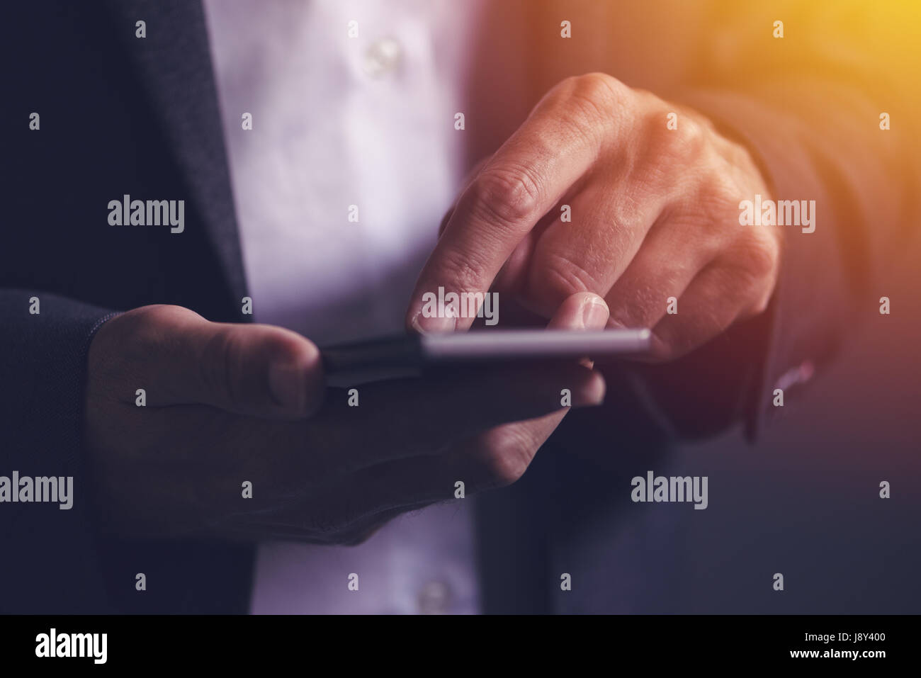 Ravvicinata di un imprenditore maschio mani utilizzando il telefono cellulare e il fuoco selettivo Foto Stock