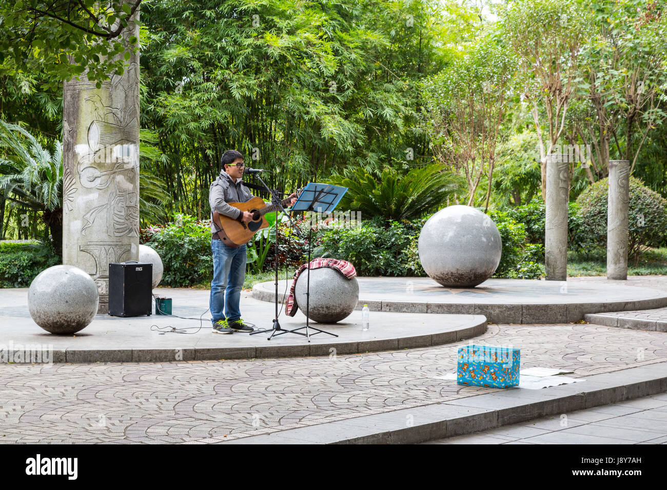 Guilin, Cina. Busker suonando la chitarra sul marciapiede della città. Foto Stock