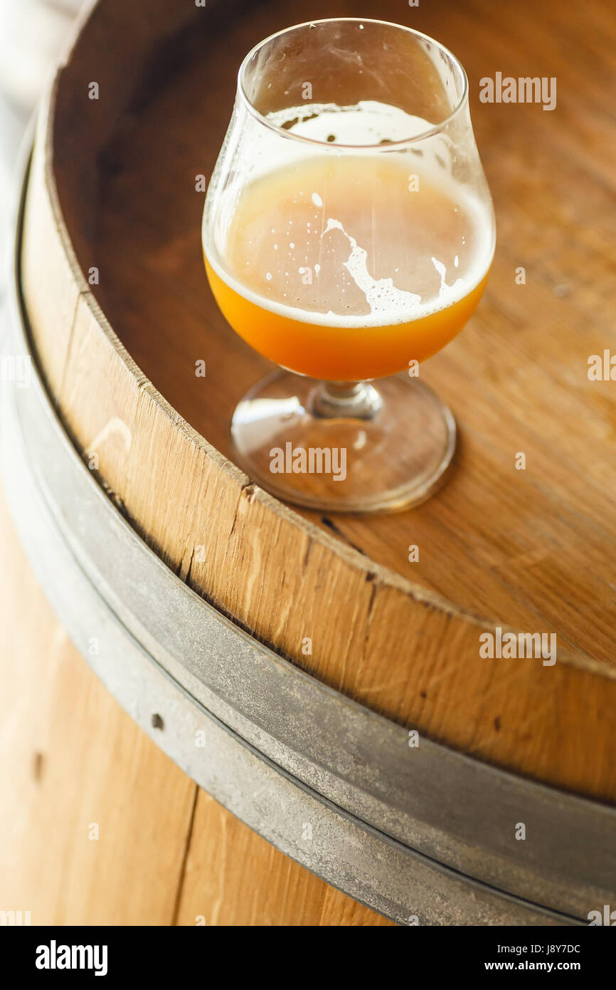 Bicchiere di birra di grano in piedi su un barile di legno in una fabbrica di birra Foto Stock