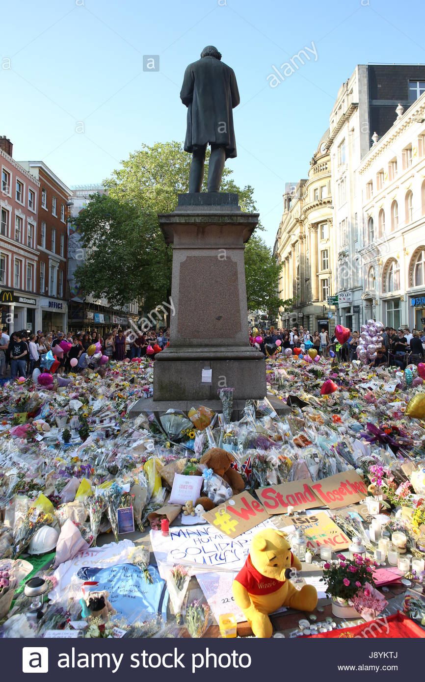 La gente di alzarsi e di rendere omaggio alle vittime dei bombardamenti di Manchester in St Ann's Square Manchester in un memoriale di fiori e altri oggetti Foto Stock