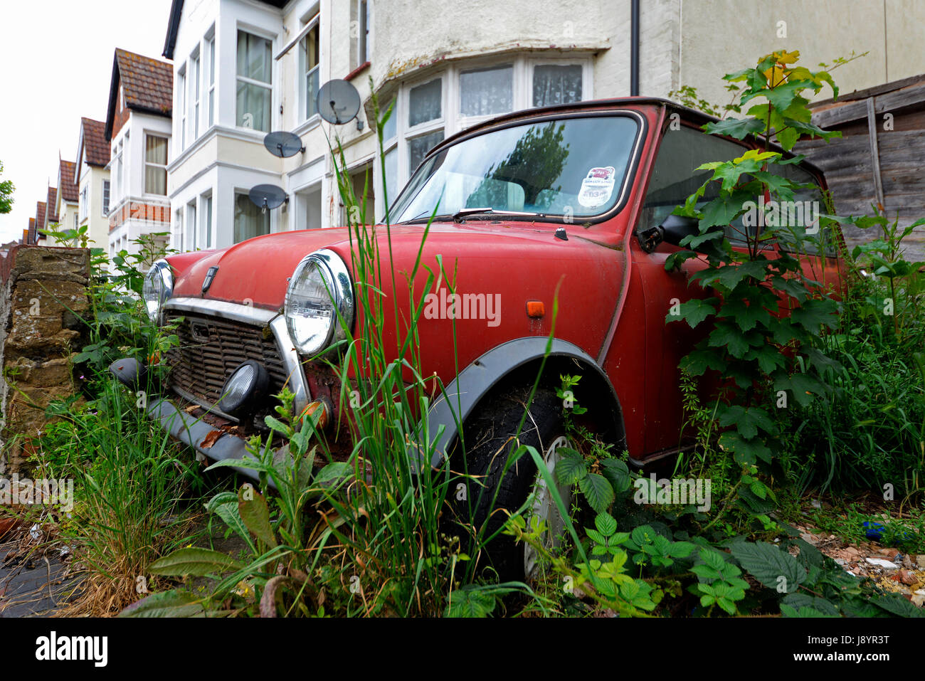 La British Leyland Mini sta decadendo e si arrugginisce in un vialetto di strada sovradimensionato a Westcliff sul Sea Essex. Con disco fiscale. Mini originale Foto Stock