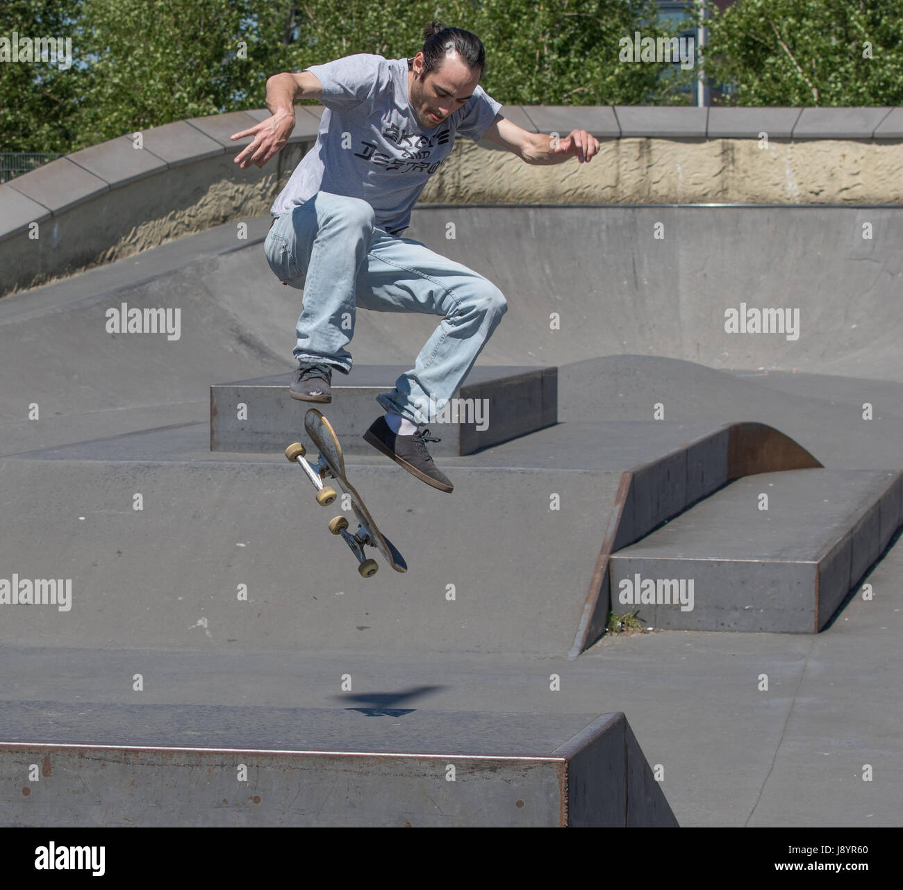 Un guidatore di skateboard eseguendo un kickflip in aria Foto Stock
