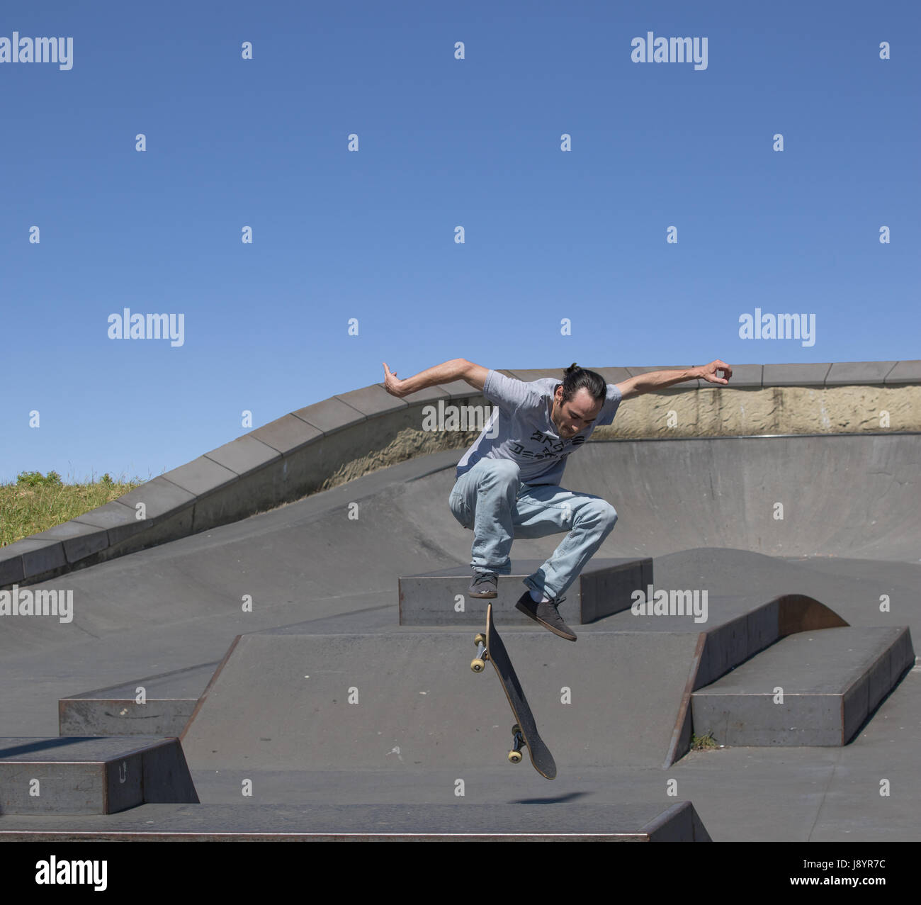 Un guidatore di skateboard eseguendo un kickflip in aria Foto Stock