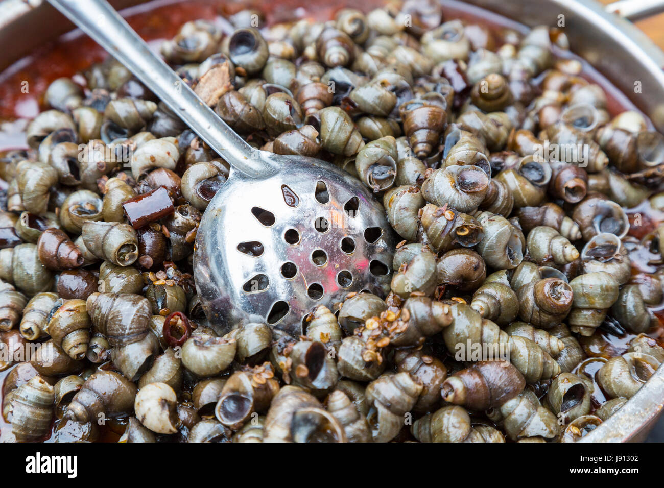 Guilin, Cina. Le lumache per la vendita su un marciapiede stand alimentari. Foto Stock