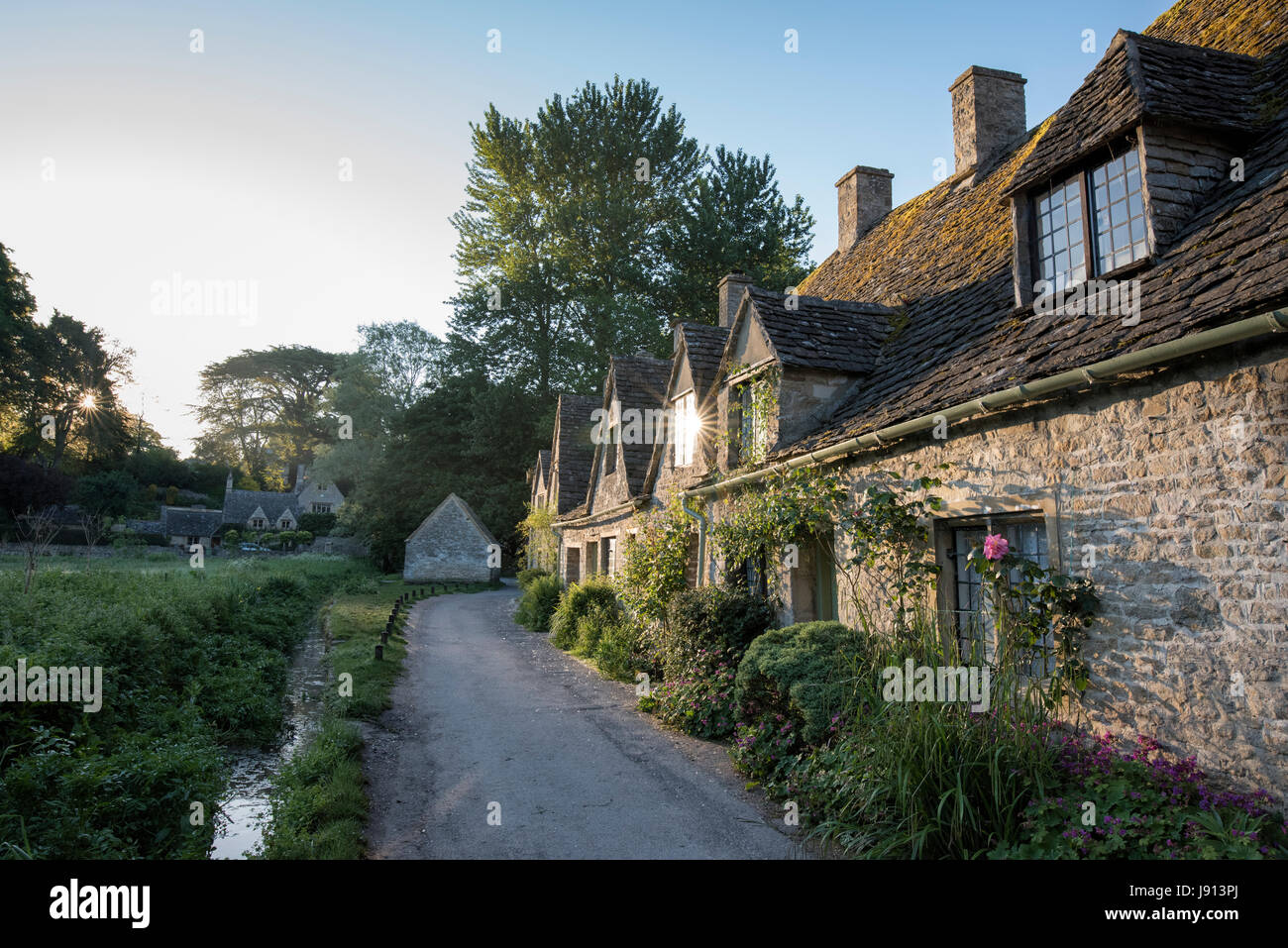 La mattina presto luce solare su Arlington Row. Bibury, Cotswolds, Gloucestershire, Inghilterra Foto Stock