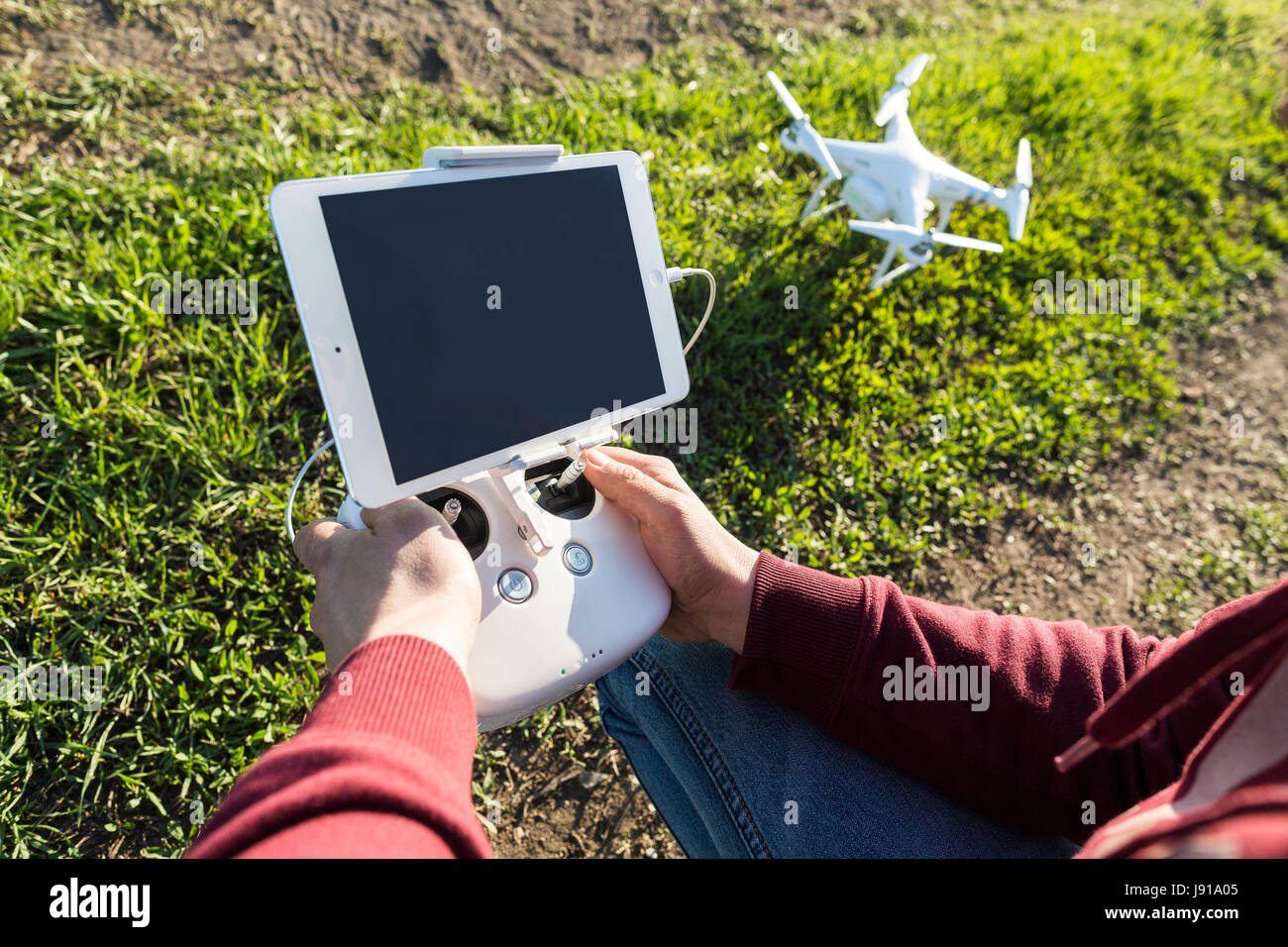 Voli quadcopter all'aperto, immagini aeree e tech hobby concetto - le mani del pilota con telecomando, tablet PC per il sondaggio di volo, la ripresa video e la fotografia aerea, il fuoco selettivo. Foto Stock