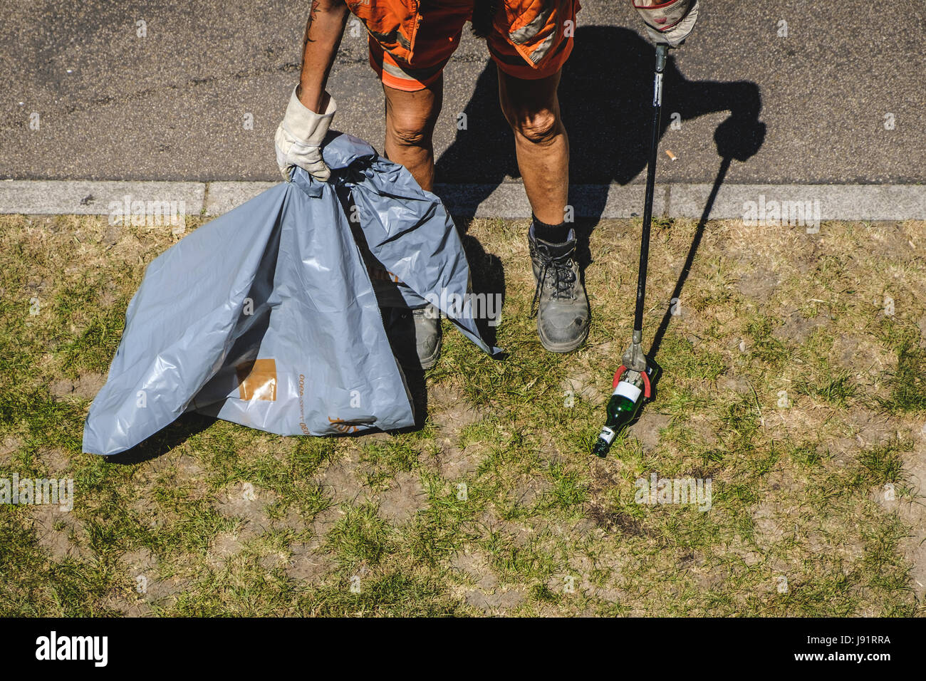 Persona parco di pulizia con un cestino con terminazione a molletta per sala - città lavoratore servizio di prelevamento di spazzatura con un grab stick Foto Stock