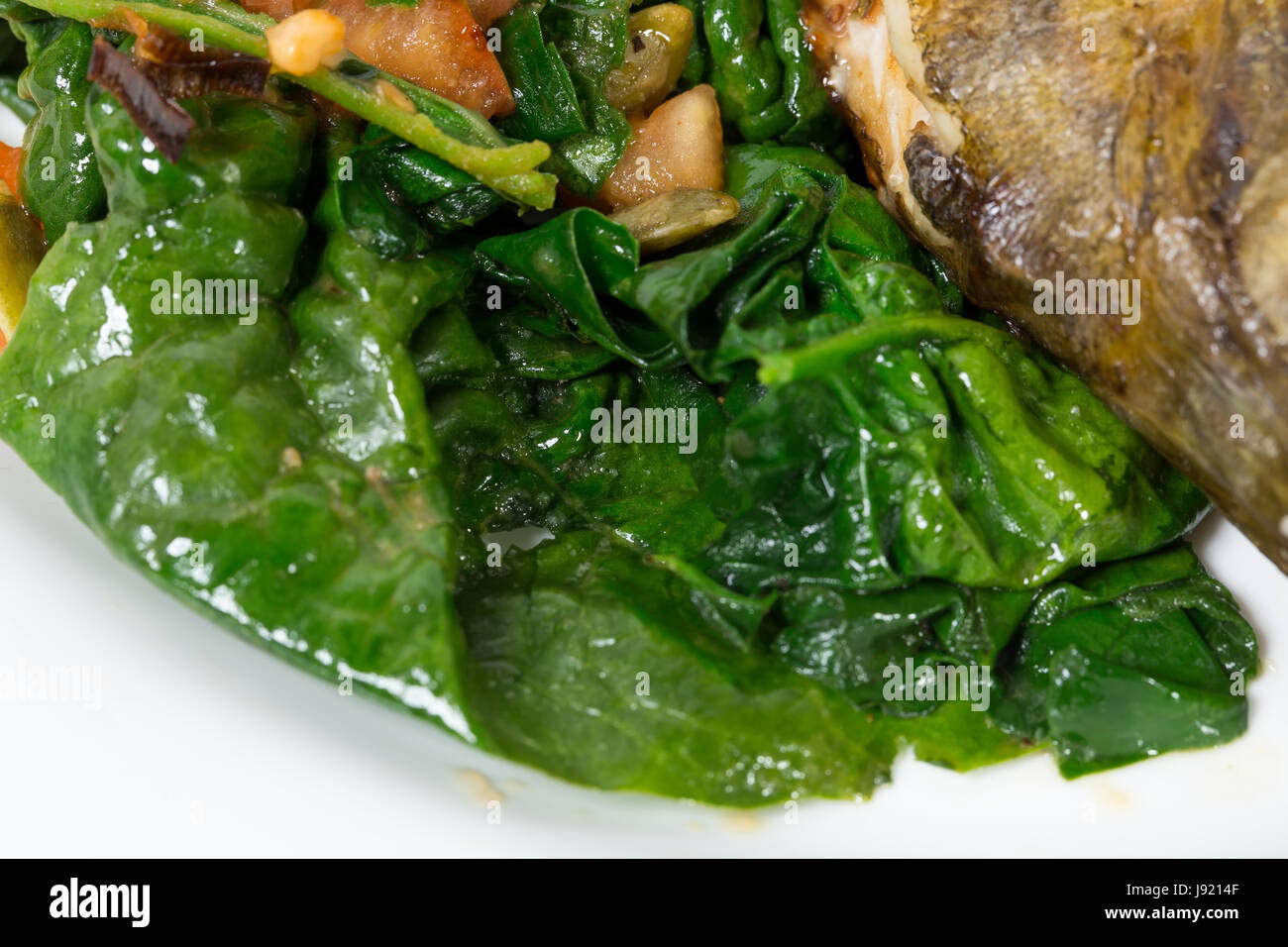 Warm insalata di spinaci con porri come guarnizione per cotto dorado. Macro. Foto può essere usato come un intero sfondo. Foto Stock