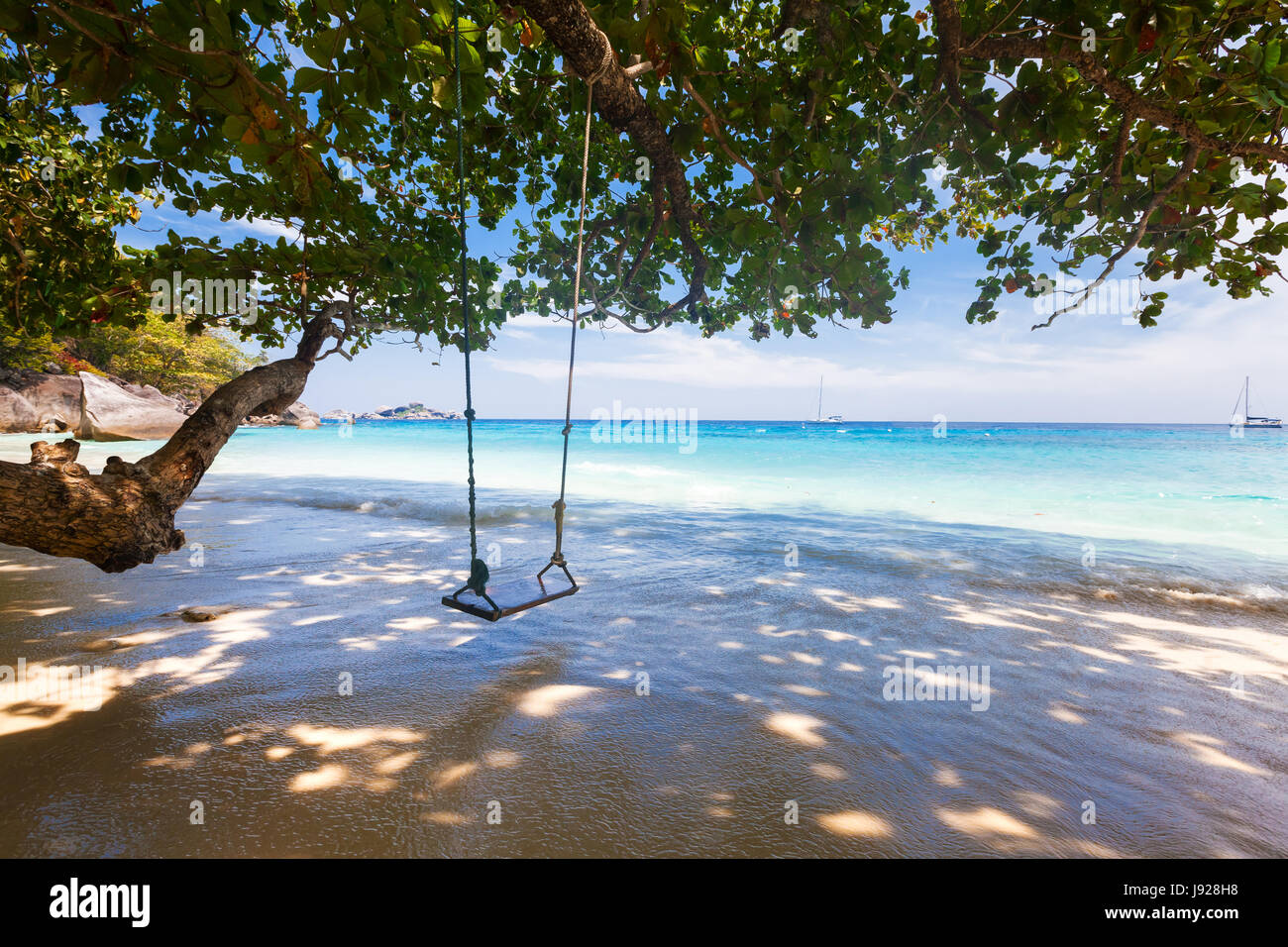 La spiaggia incontaminata con acqua turchese e swing corda, fogliame verde Foto Stock