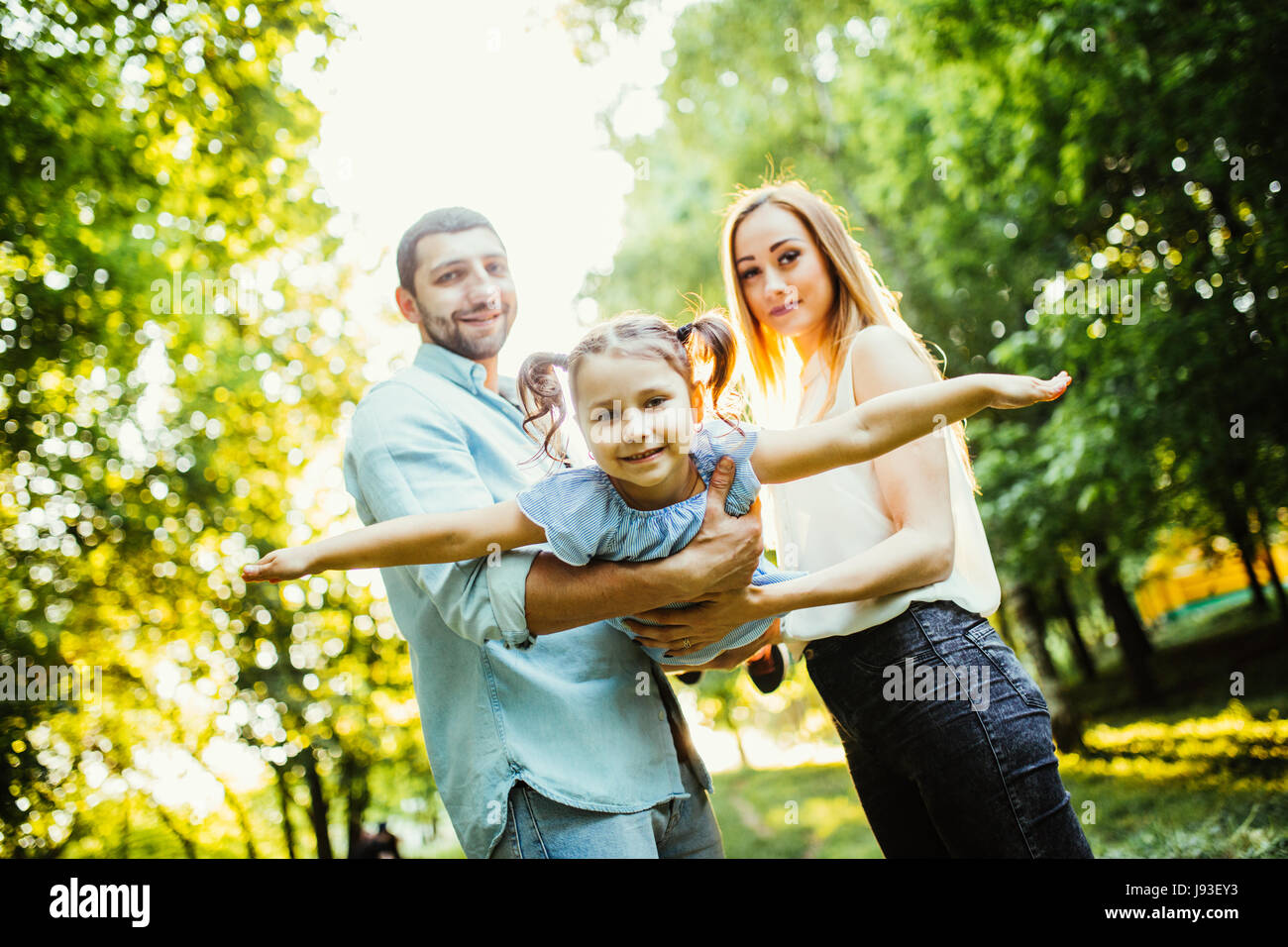 La famiglia felice con un bambino divertirsi insieme in estate il parco della città Foto Stock