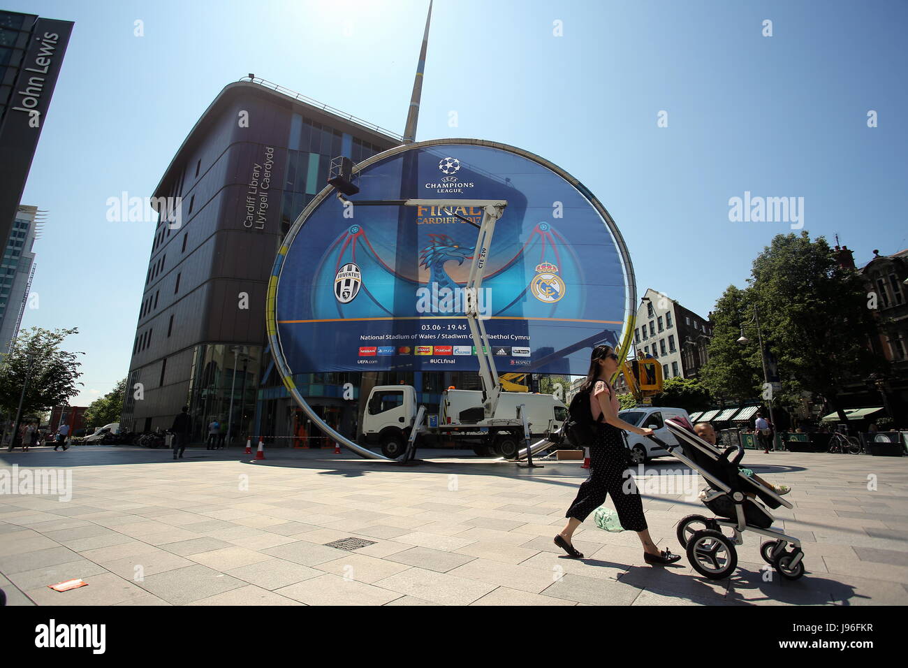 Lavoratori fissare un gigante di UEFA Champions League banner al di fuori dell'edificio della Biblioteca del Hayes, Cardiff. Foto Stock