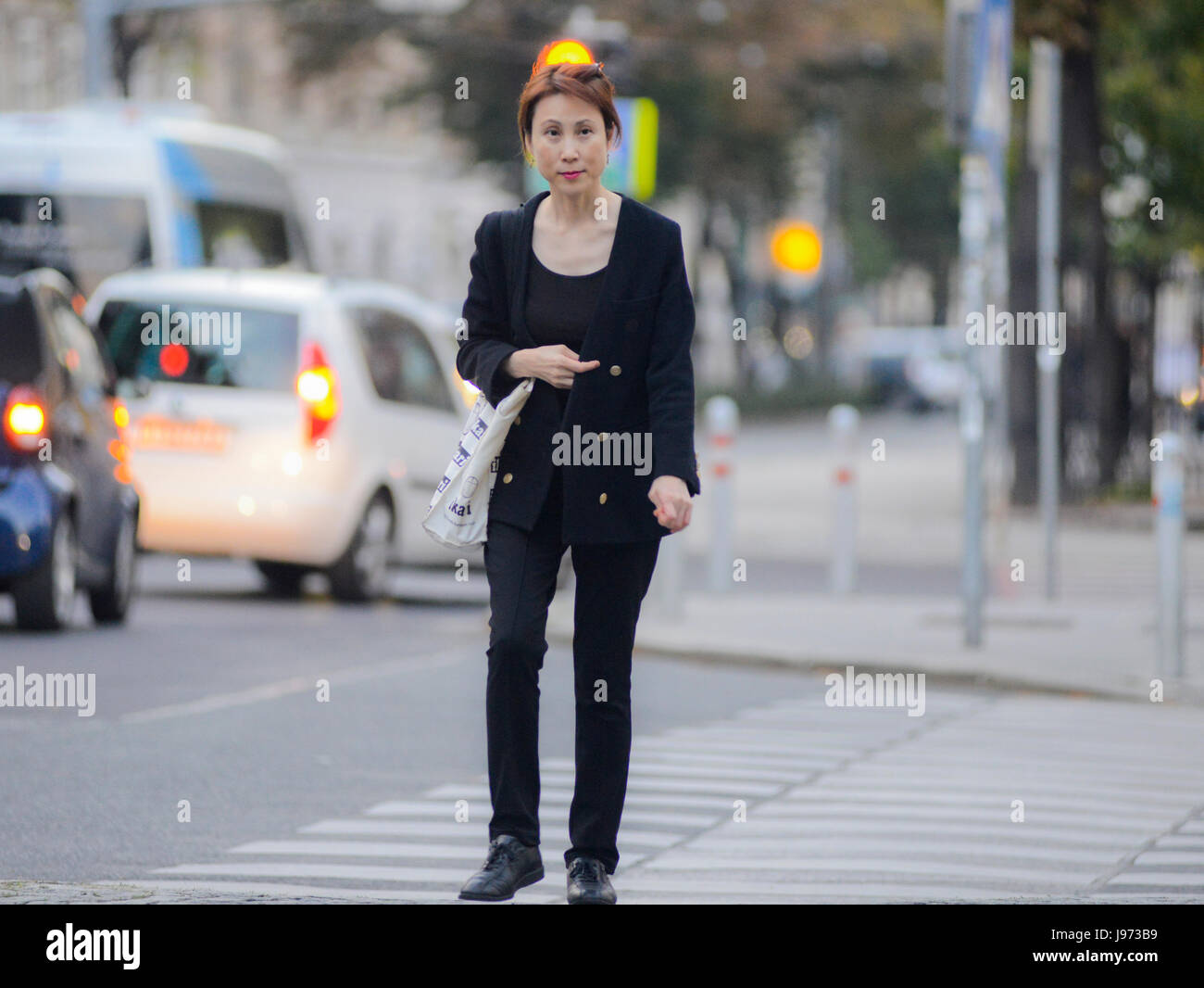 Donna asiatica a piedi attraversando una strada Foto Stock