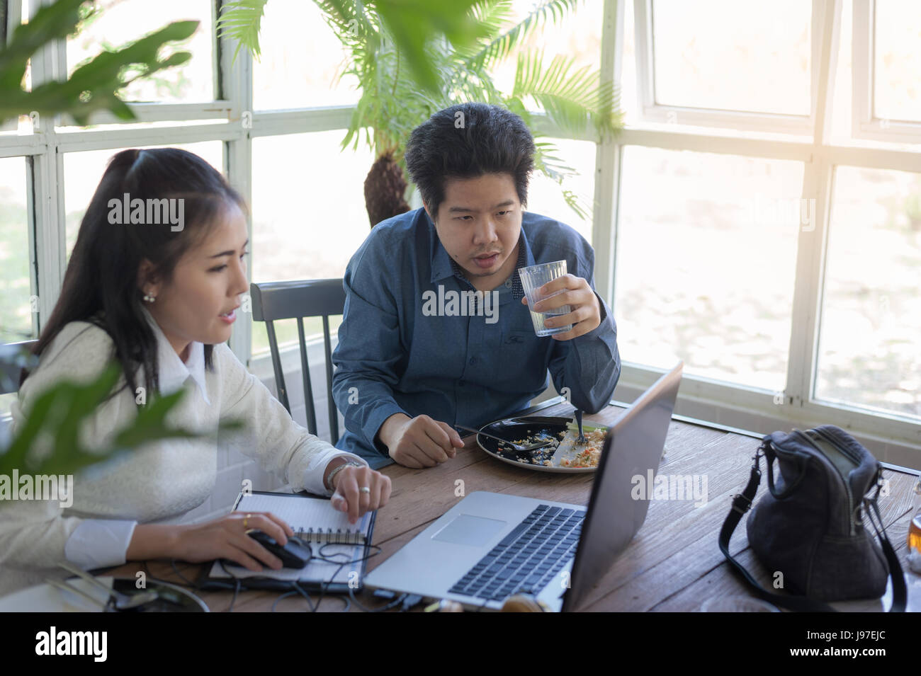 Giovani asiatici imprenditore e imprenditrice parlando di loro lavoro mentre guardando il monitor di un laptop in coffee shop. Startup business per freelance lavoro Foto Stock