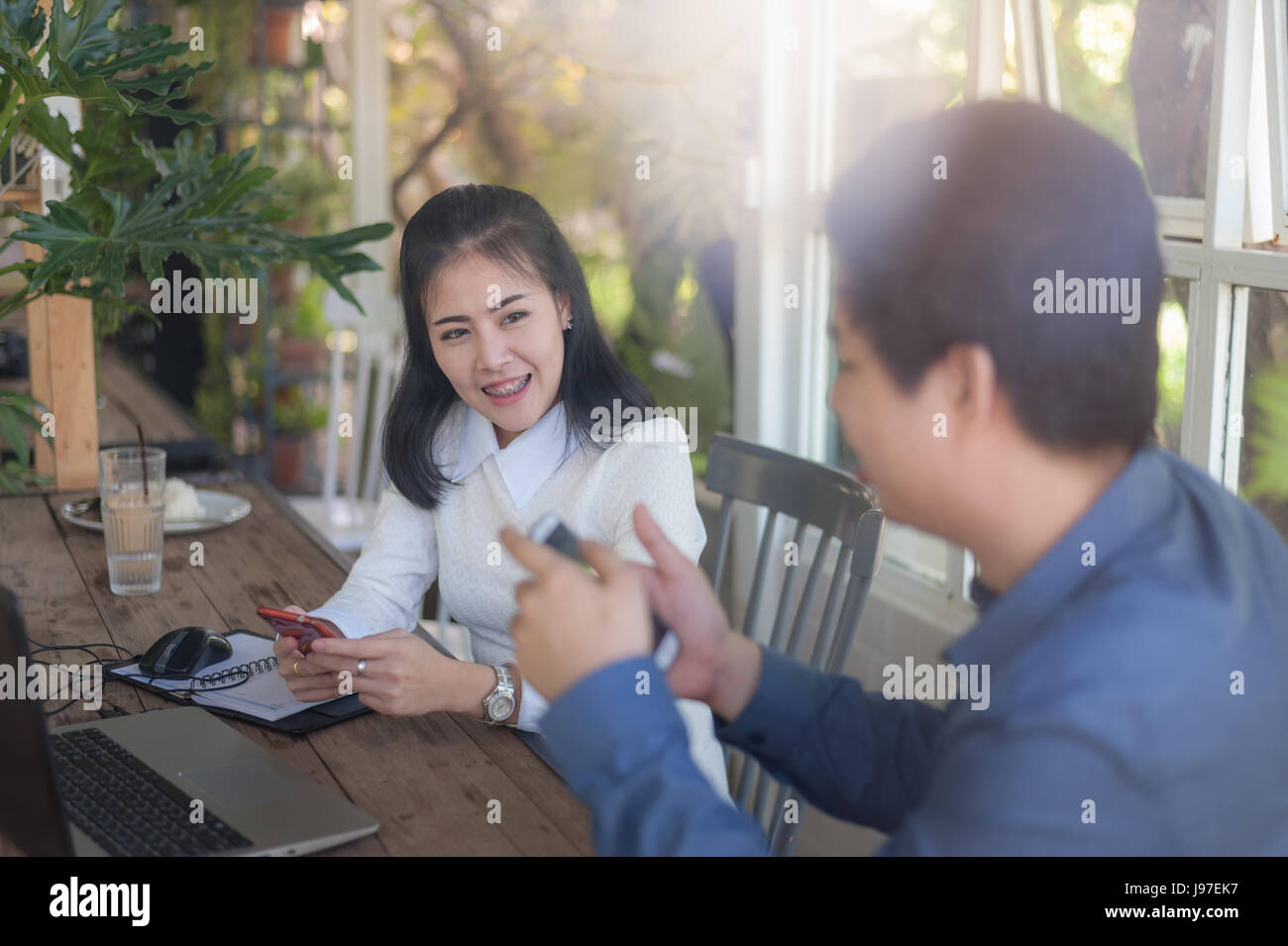 Giovani asiatici imprenditore e imprenditrice parlando di loro lavoro mentre guardando il monitor di un laptop in coffee shop. Startup business per freelance lavoro Foto Stock