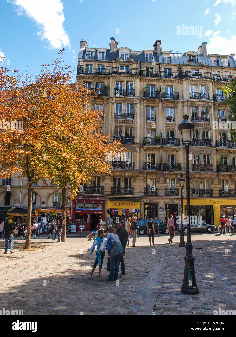 Paris Street scene in autunno con arancio. Regione di Montmartre a Parigi, Francia. Strada di ciottoli è fiancheggiata da alberi e pali della luce. Foto Stock