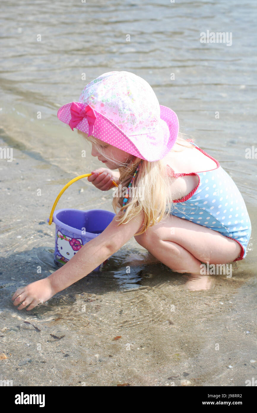 Bambina bambino raccogli conchiglie sulla spiaggia con una benna indossando  un cappello, in Dublino Irlanda Foto stock - Alamy