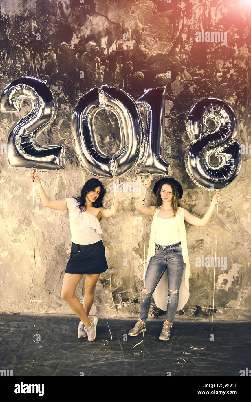 Due giovani ragazza celebra il 2018 con grandi ballons che forme 2018 su un cinema sfondo rétro Foto Stock
