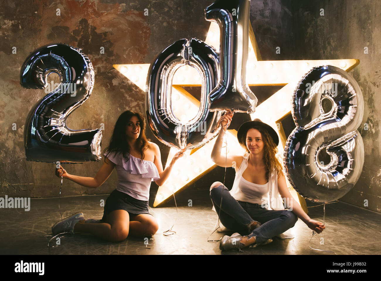 Due giovani ragazza celebra il 2018 con grandi ballons che forme 2018 su un cinema sfondo rétro Foto Stock