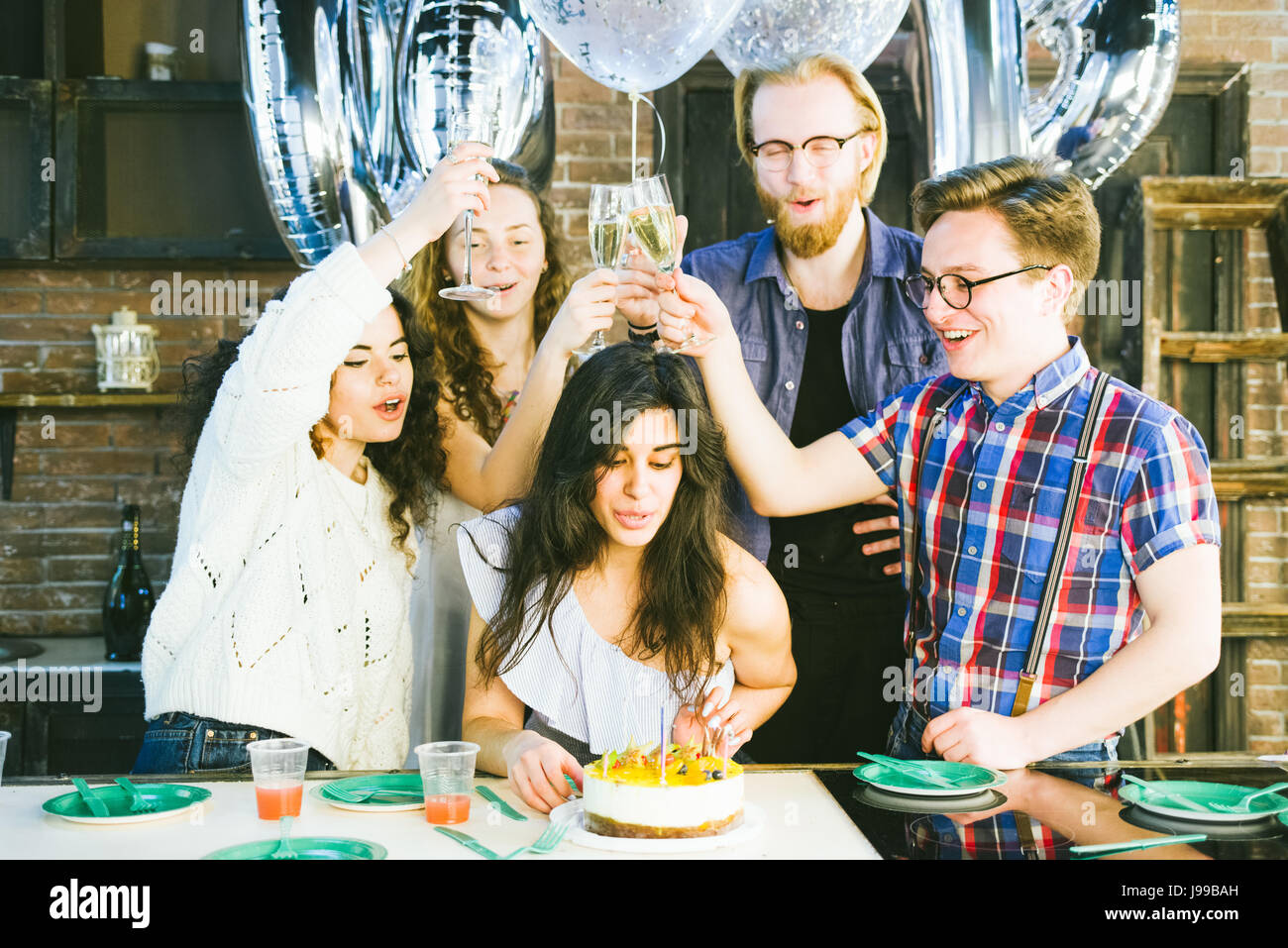 Giovane ragazza festeggia il suo compleanno soffiando fuori le candele con i suoi amici,flare utilizzati per aumentare l'umore e i toni di composizione Foto Stock