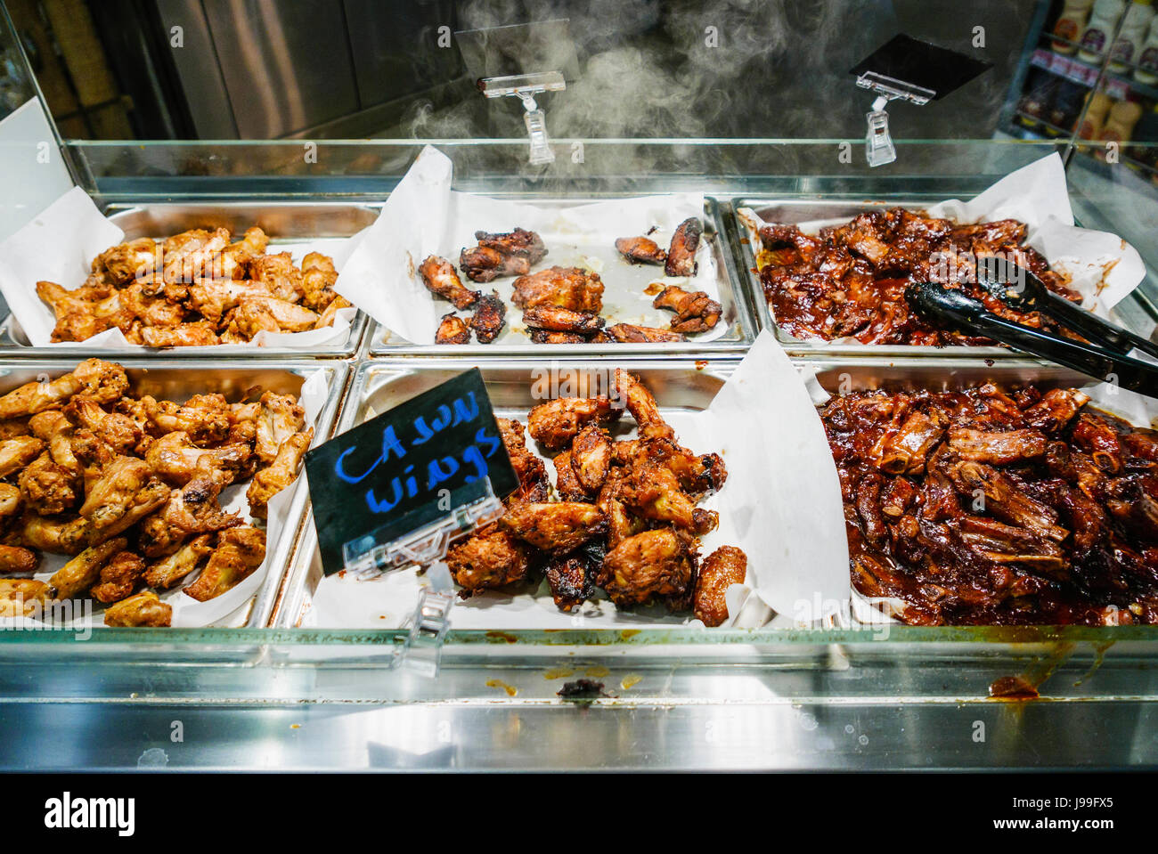 Sud-fritto, cajun e cinese hot ali di pollo in vendita a caldo il bancone di un supermercato. Foto Stock