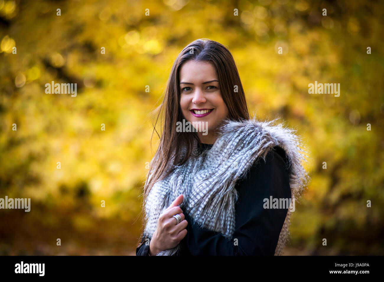 Signora giovane godendo di caldi colori autunnali nei boschi circondate da acero canadese lasciare gli alberi e il giapponese acer alberi di acero, sfumature di rosso, arancione Foto Stock